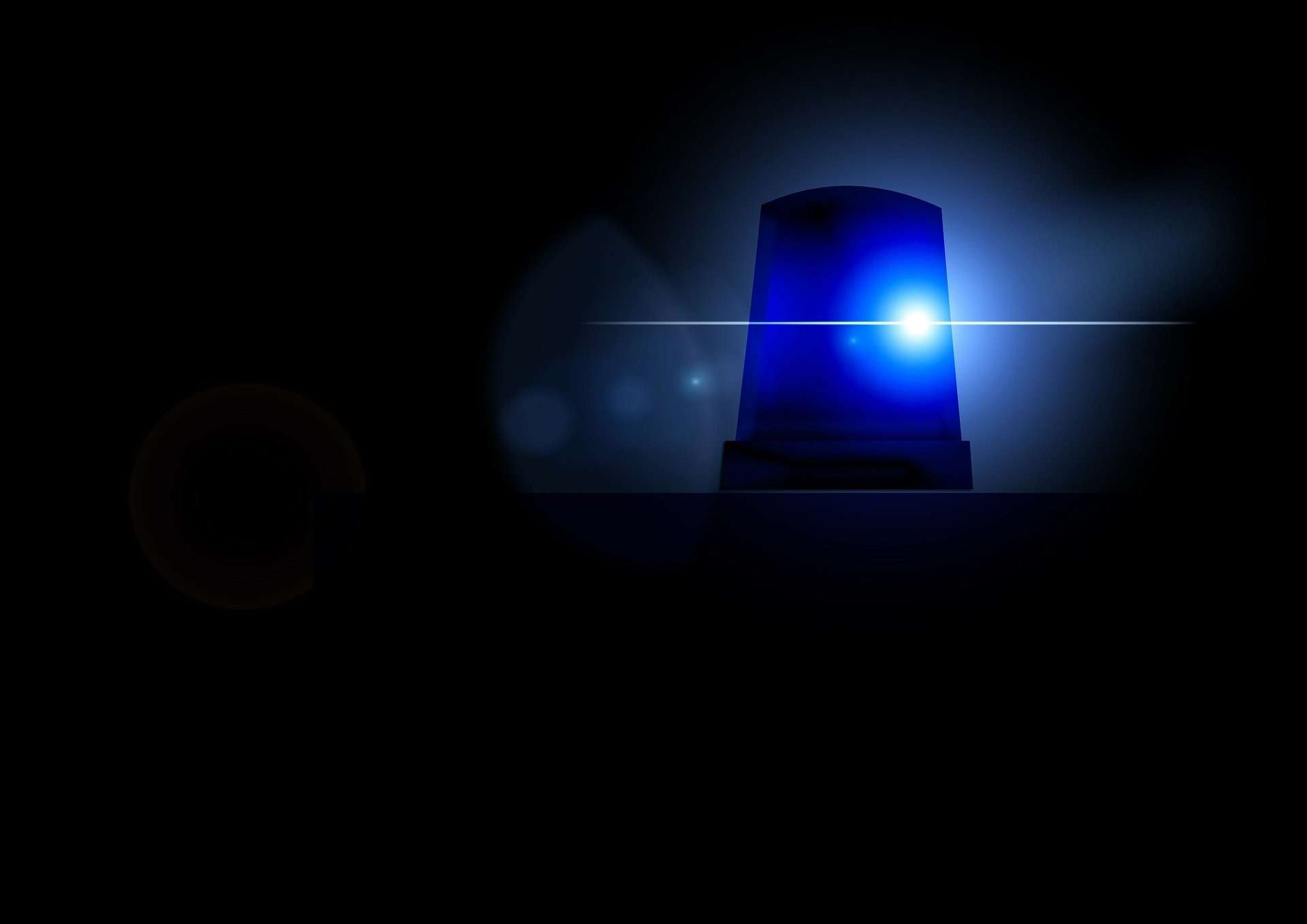 blue police beacon on the top of a car in the dark